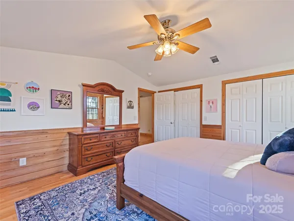 a bedroom with a bed and dresser with wooden floor