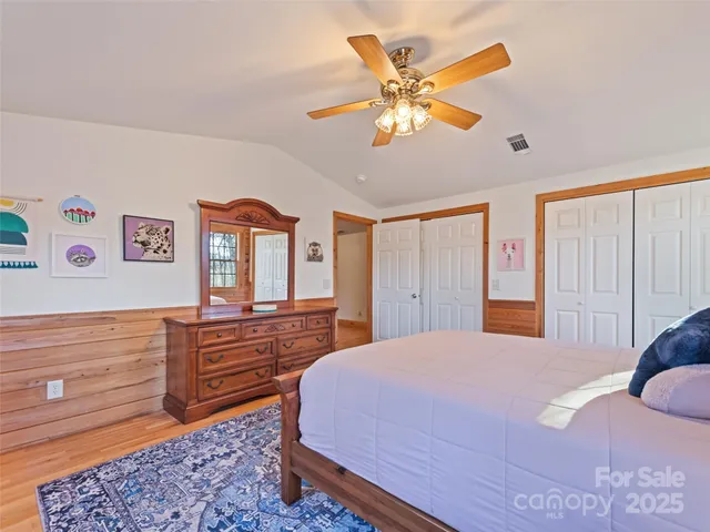 a bedroom with a bed and dresser with wooden floor