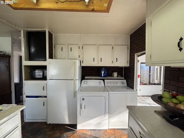 a kitchen with a refrigerator a stove a sink dishwasher and white countertops with wooden floor