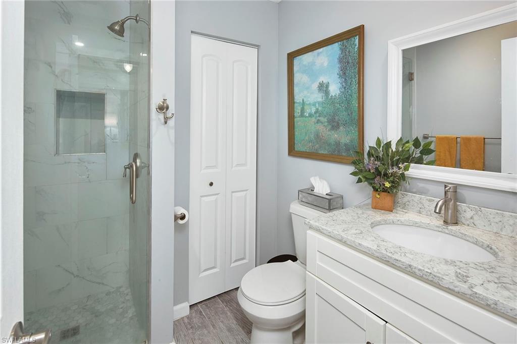 1343 12th Street North Naples, FL 34102 - Photo 11 of 18 a bathroom with a granite countertop sink a toilet and shower