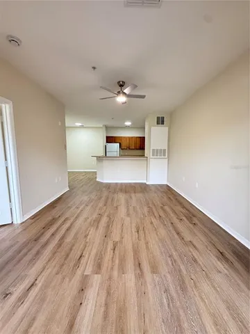 a view of empty room with wooden floor and fan