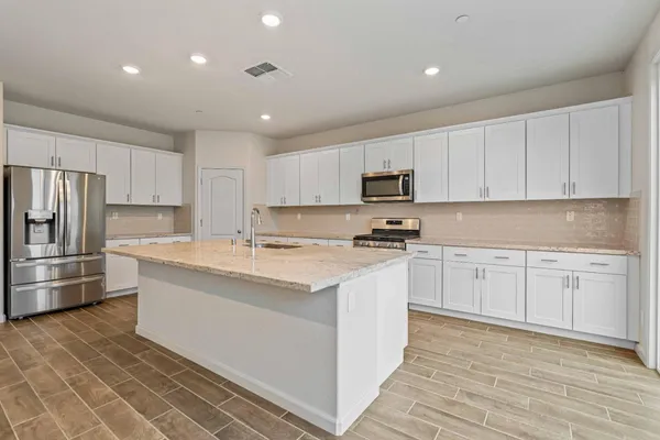 a kitchen with granite countertop a refrigerator stove top oven and sink