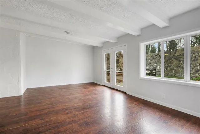 a view of an empty room with wooden floor and a window