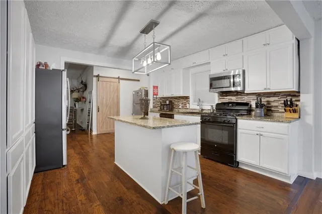 a kitchen with kitchen island granite countertop a sink cabinets and stainless steel appliances