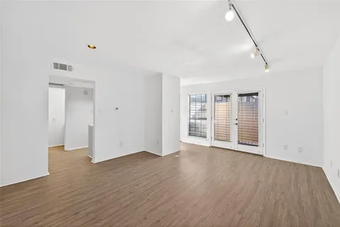 a view of an empty room with wooden floor and windows