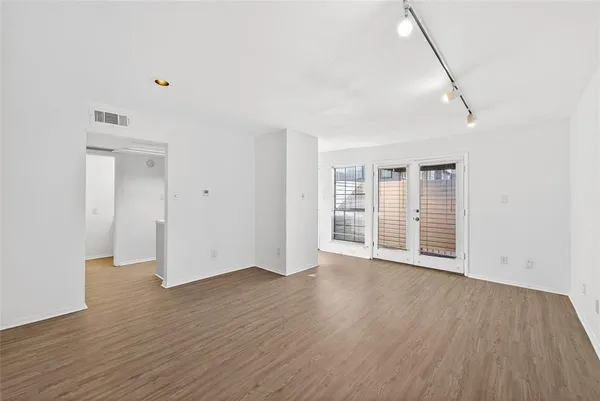 a view of an empty room with wooden floor and windows