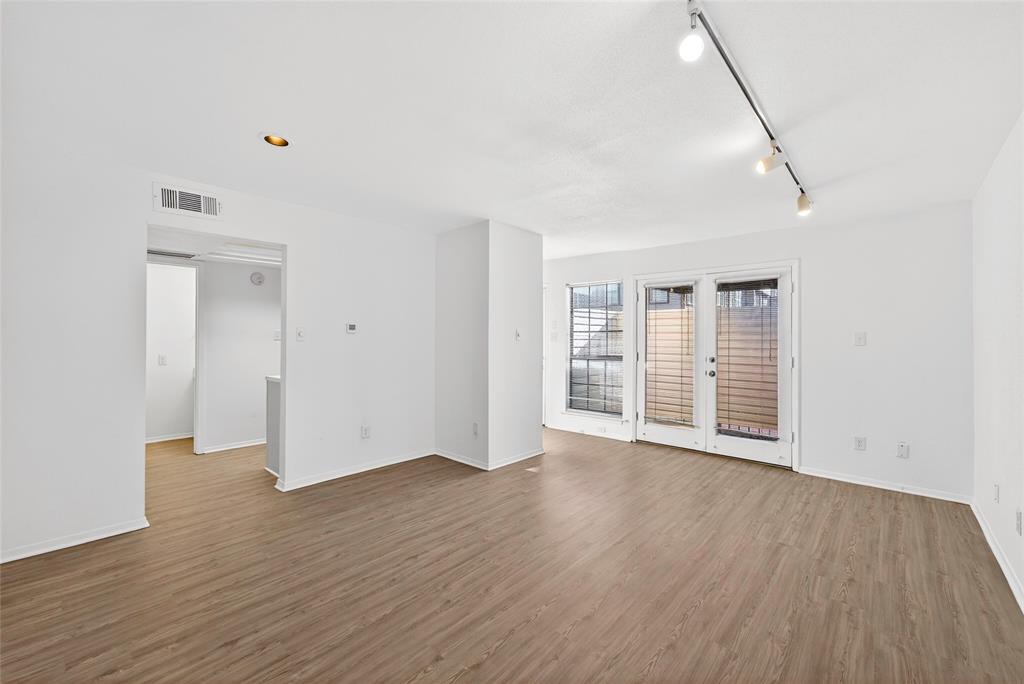 a view of an empty room with wooden floor and windows