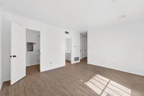 an empty room with wooden floor & windows