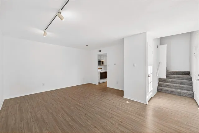 a view of an empty room with wooden floor and stairs