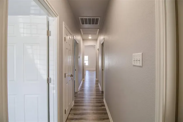 a view of a hallway with wooden floor and a bathroom