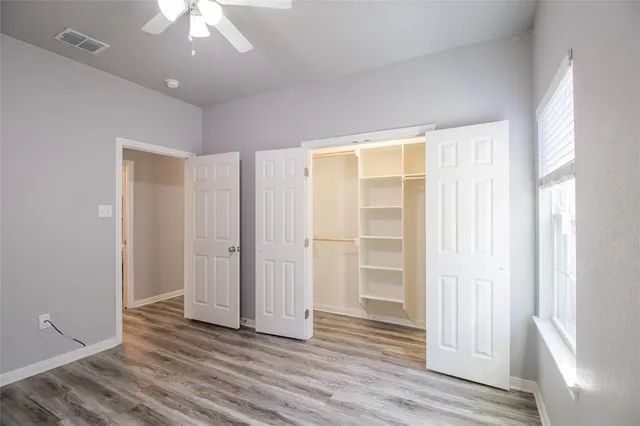 an empty room with a window and ceiling fan