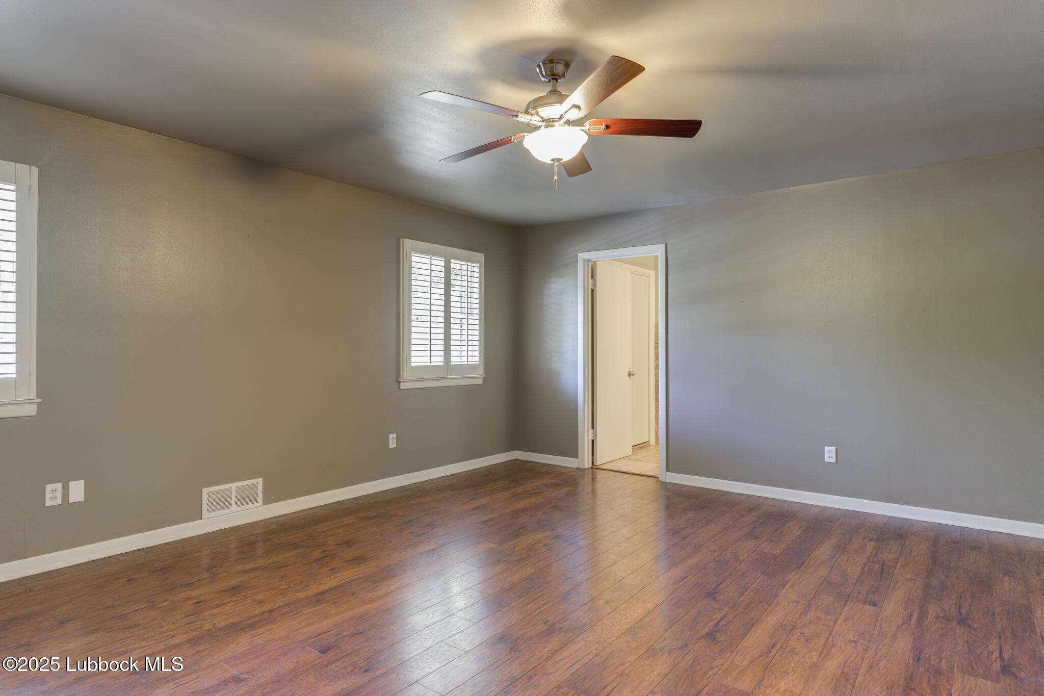 4608 18th Street Lubbock, TX 79416 - Photo 62 of 84 a view of an empty room with wooden floor and a ceiling fan