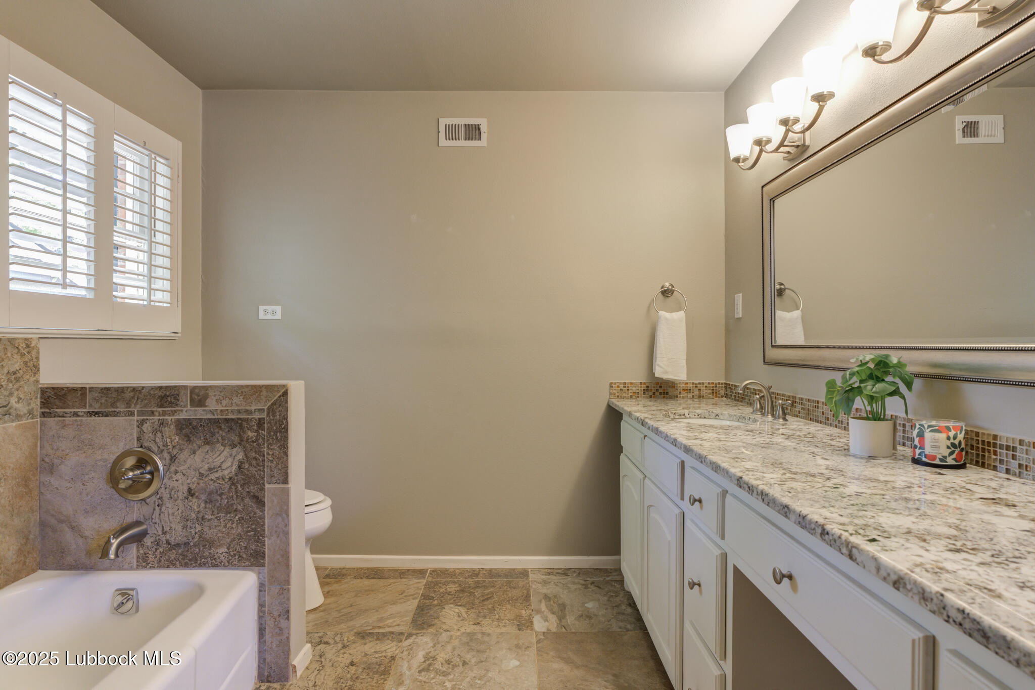4608 18th Street Lubbock, TX 79416 - Photo 65 of 84 a bathroom with a granite countertop sink and a mirror