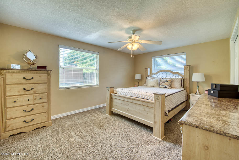 5128 Spring Glen Road Jacksonville, FL 32207 - Photo 12 of 24 a spacious bedroom with a bed and a chandelier