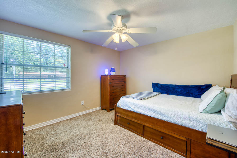 5128 Spring Glen Road Jacksonville, FL 32207 - Photo 18 of 24 a bedroom with a bed and a chandelier