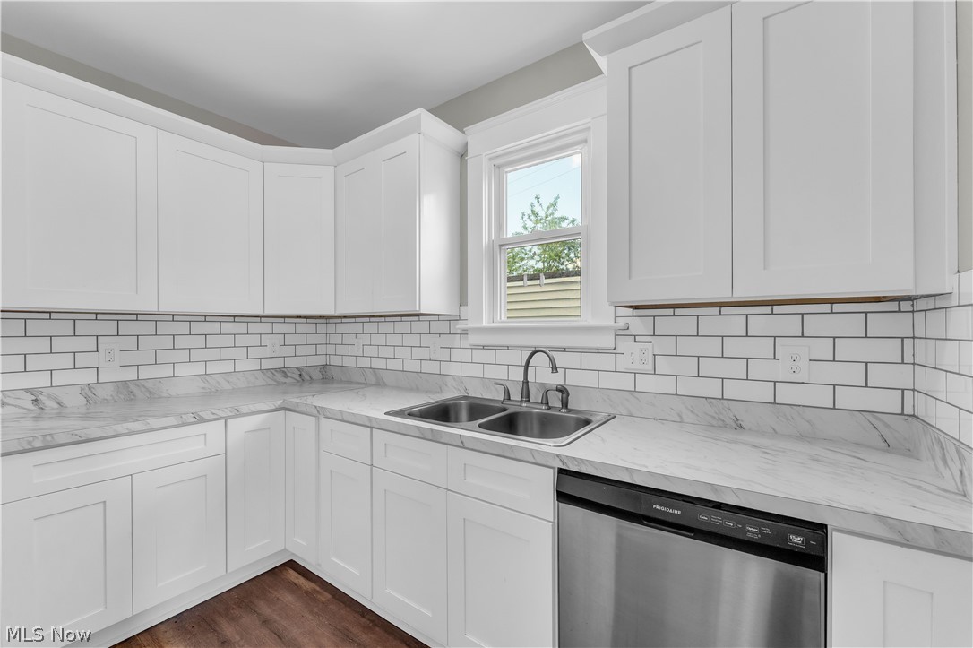 3506 Riverside Avenue Cleveland, OH 44109 - Photo 16 of 31 Kitchen featuring white shaker cabinetry, subway tile backsplash, light-toned countertops, stainless steel double basin sink, and a stainless steel dishwasher