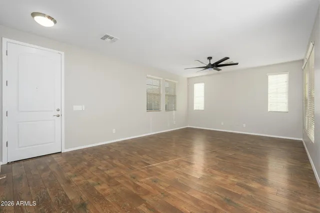 a view of empty room with wooden floor and fan