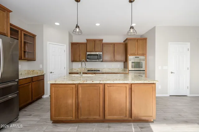 a kitchen with kitchen island granite countertop wooden cabinets and refrigerator