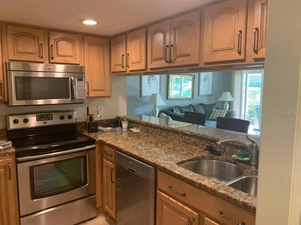 a kitchen with granite countertop a sink stove and microwave