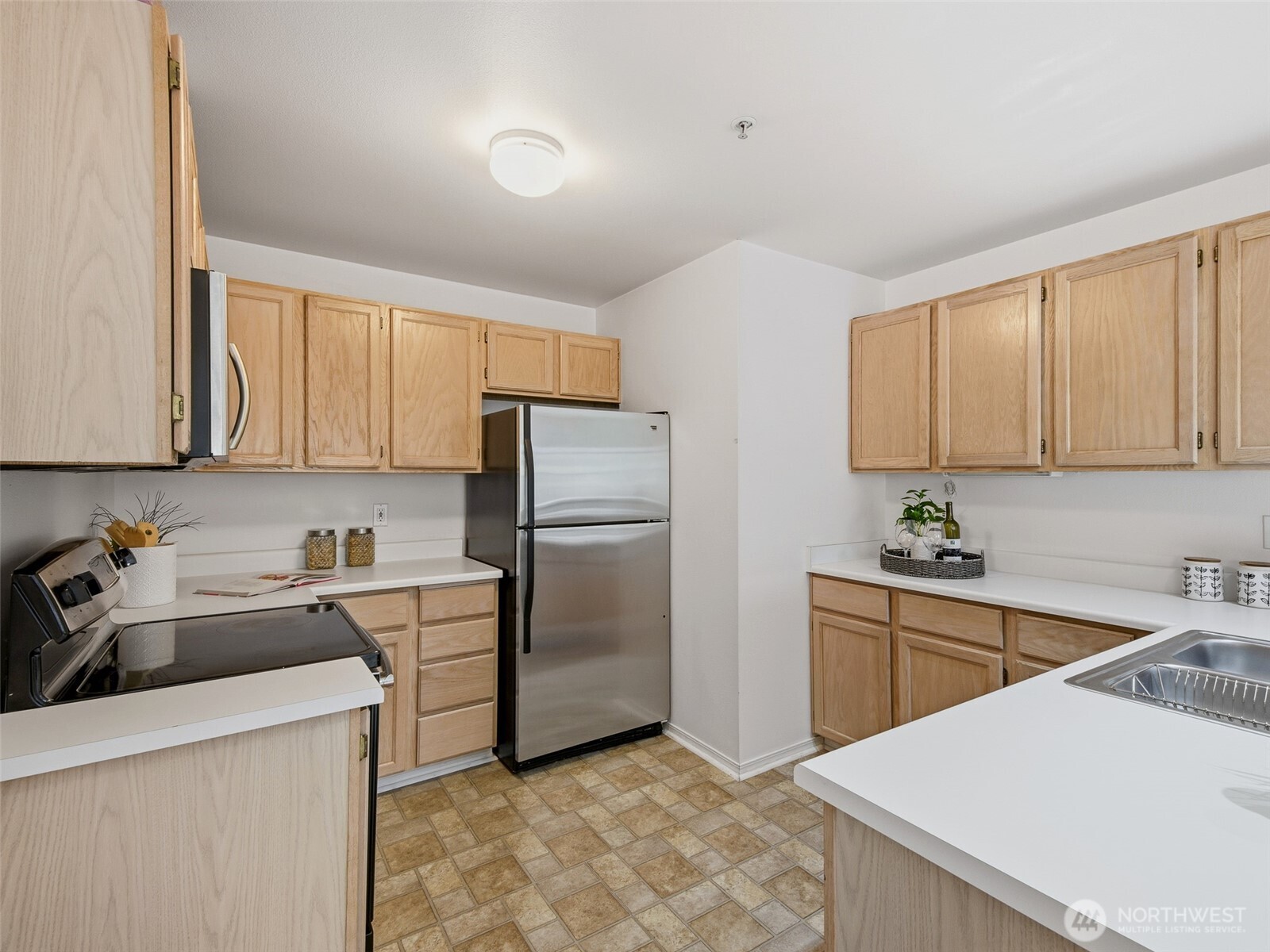 1733 Northwest 59th Street, Unit 301 Seattle, WA 98107 - Photo 6 of 35 a kitchen with a sink a refrigerator and cabinets