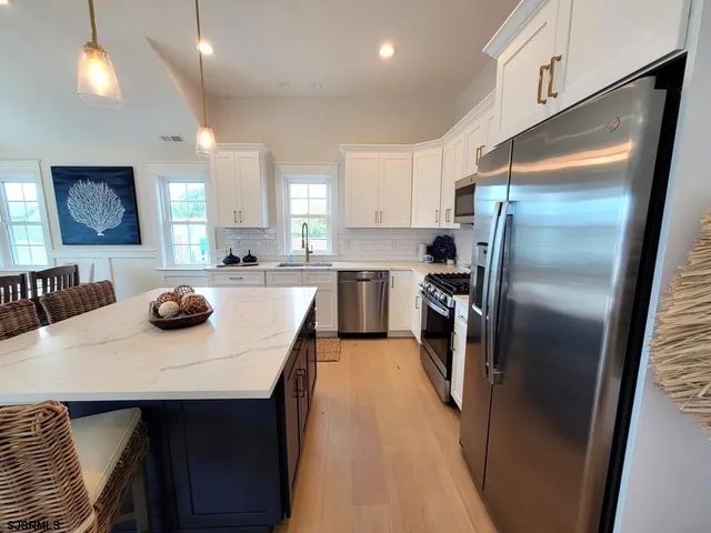 a kitchen with stainless steel appliances a refrigerator a sink a stove and a refrigerator