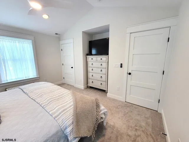 a bedroom with a large bed and a flat tv screen