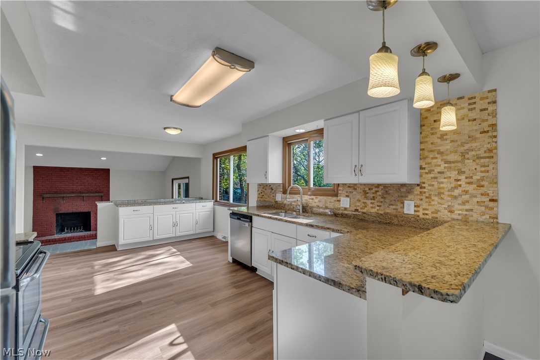2540 Charney Road University Heights, OH 44118 - Photo 13 of 44 Kitchen featuring white cabinetry, stone-finish countertops, tile backsplash, stainless steel sink, and wood-finish flooring