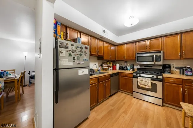 a kitchen with stainless steel appliances granite countertop a refrigerator a stove top oven a sink and dishwasher