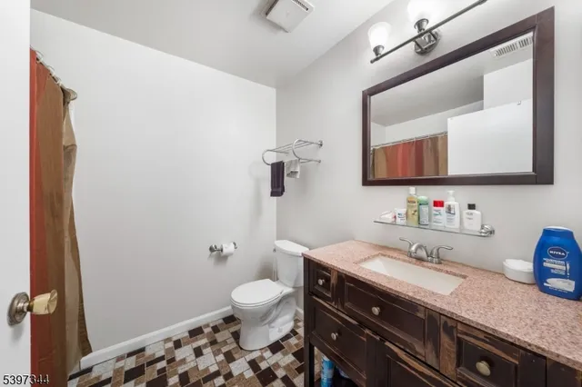 a bathroom with a granite countertop toilet sink and mirror