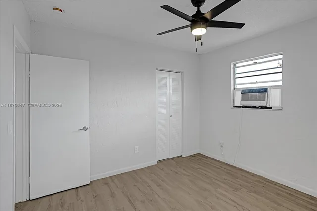 a view of empty room with wooden floor and fan