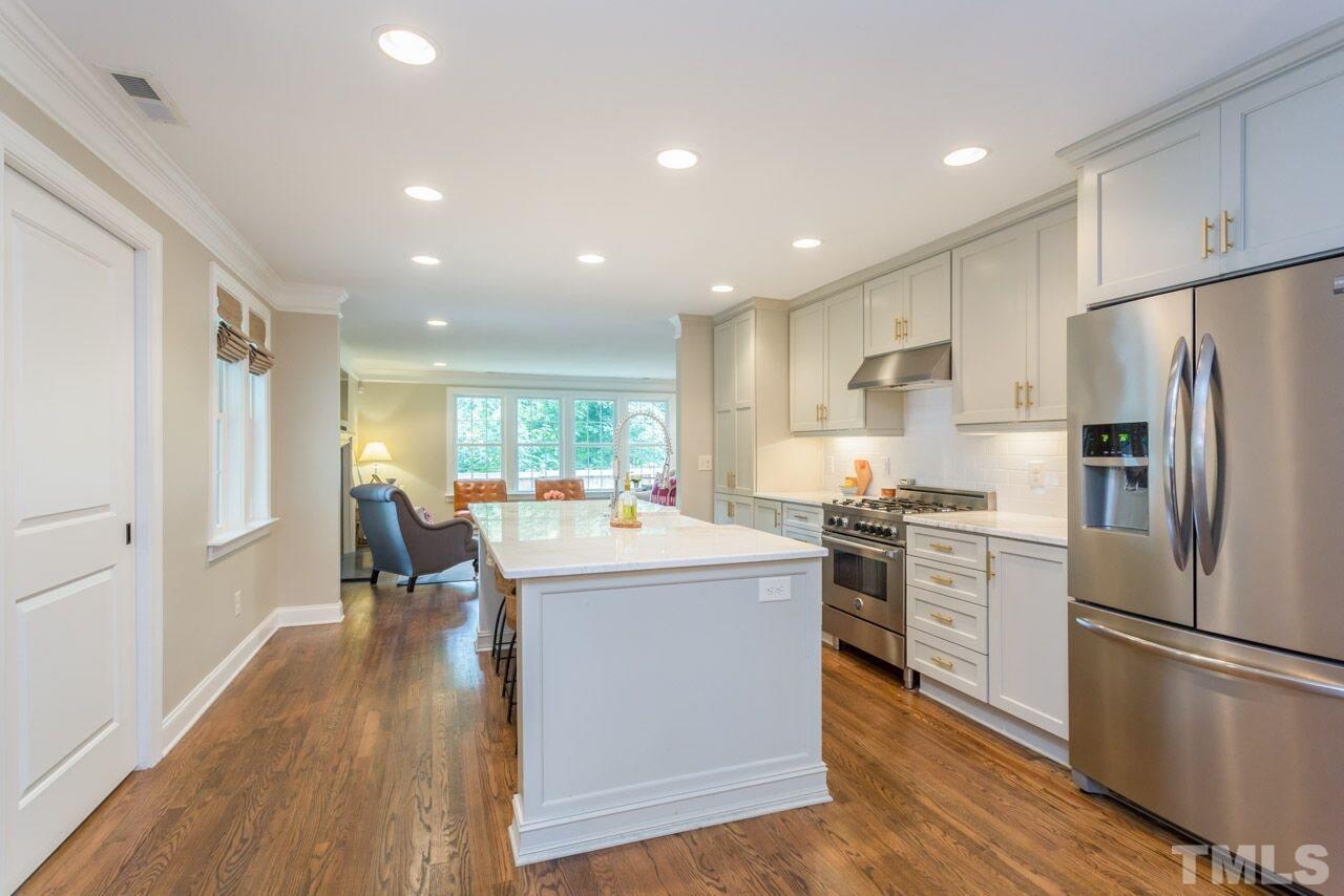 2818 Fowler Avenue Raleigh, NC 27607 - Photo 8 of 25 a kitchen with stainless steel appliances a refrigerator a stove a sink dishwasher and a dining table with wooden floor