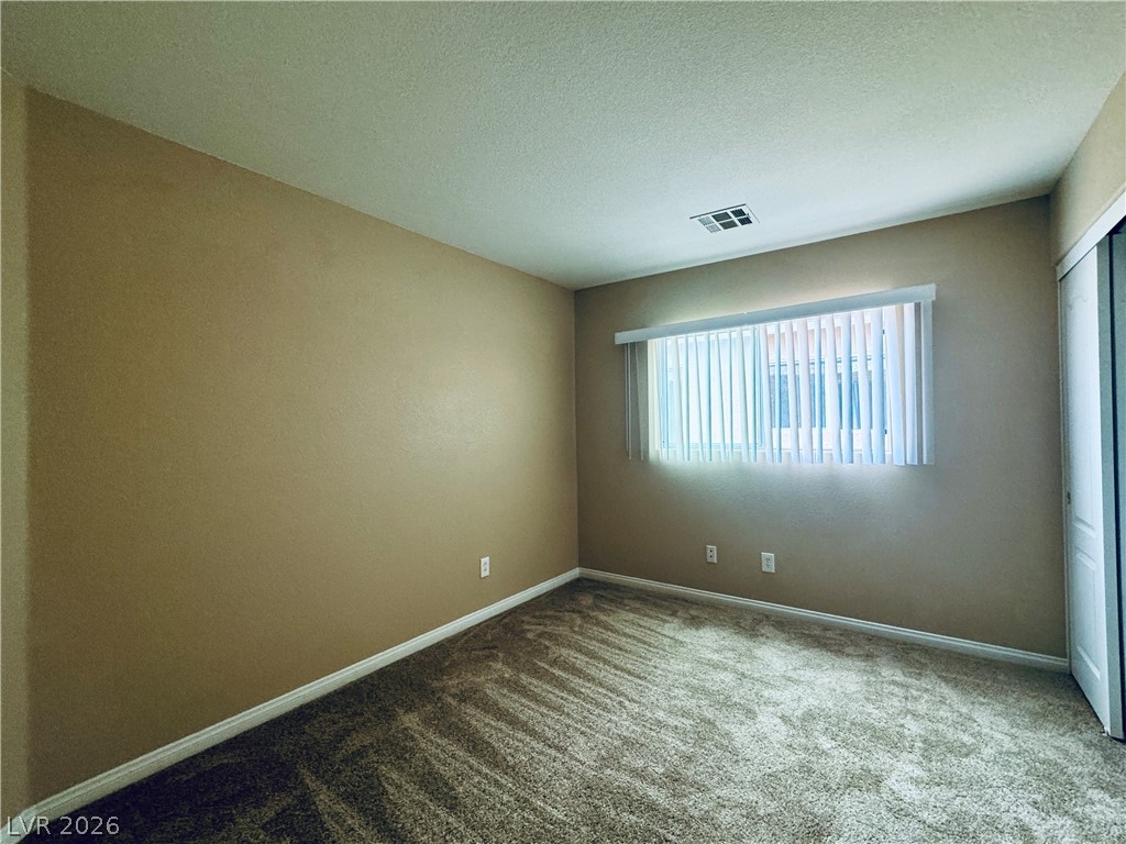 8617 Palomino Ranch Street Las Vegas, NV 89131 - Photo 16 of 27 A well-lit bedroom features plush carpeting and a wide window with vertical blinds, offering a calm personal retreat.