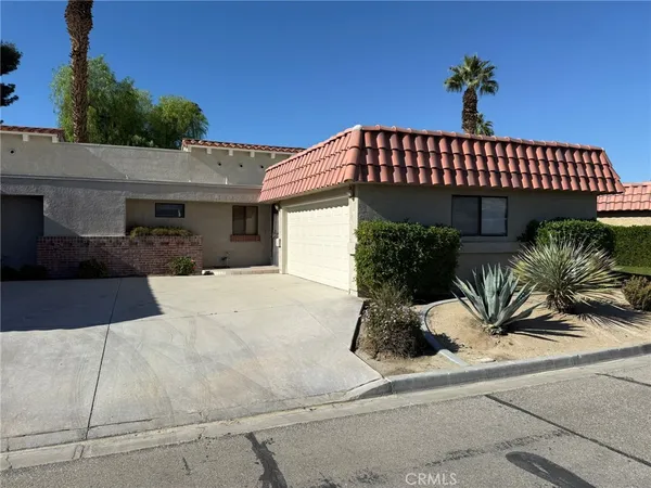 a view of a house with a yard and potted plants