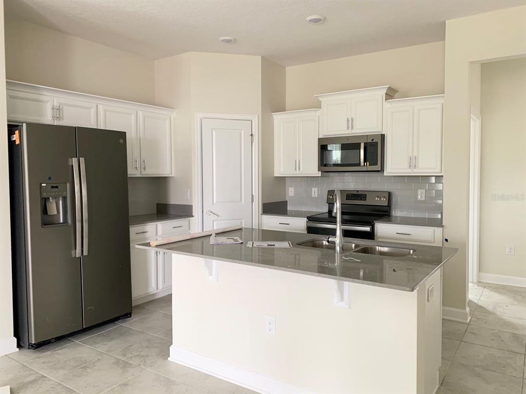 16147 Water Spring Boulevard Winter Garden, FL 34787 - Photo 2 of 17 a kitchen with stainless steel appliances granite countertop a refrigerator a stove a sink and a granite counter tops