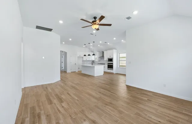 a large kitchen with granite countertop a large counter top a sink stainless steel appliances and cabinets