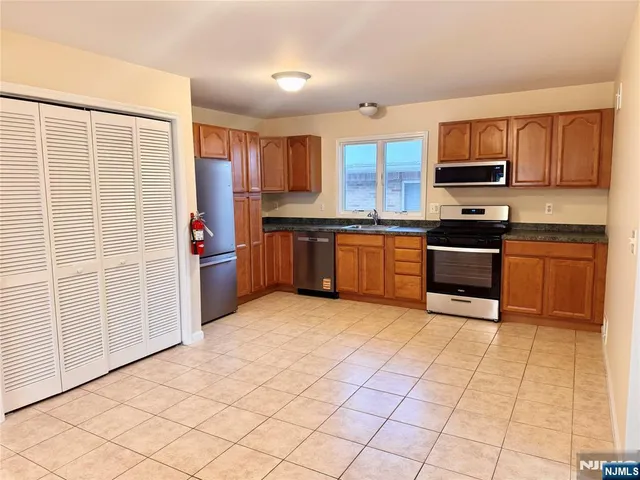 a kitchen with stainless steel appliances granite countertop a stove top oven a sink a counter space and cabinets