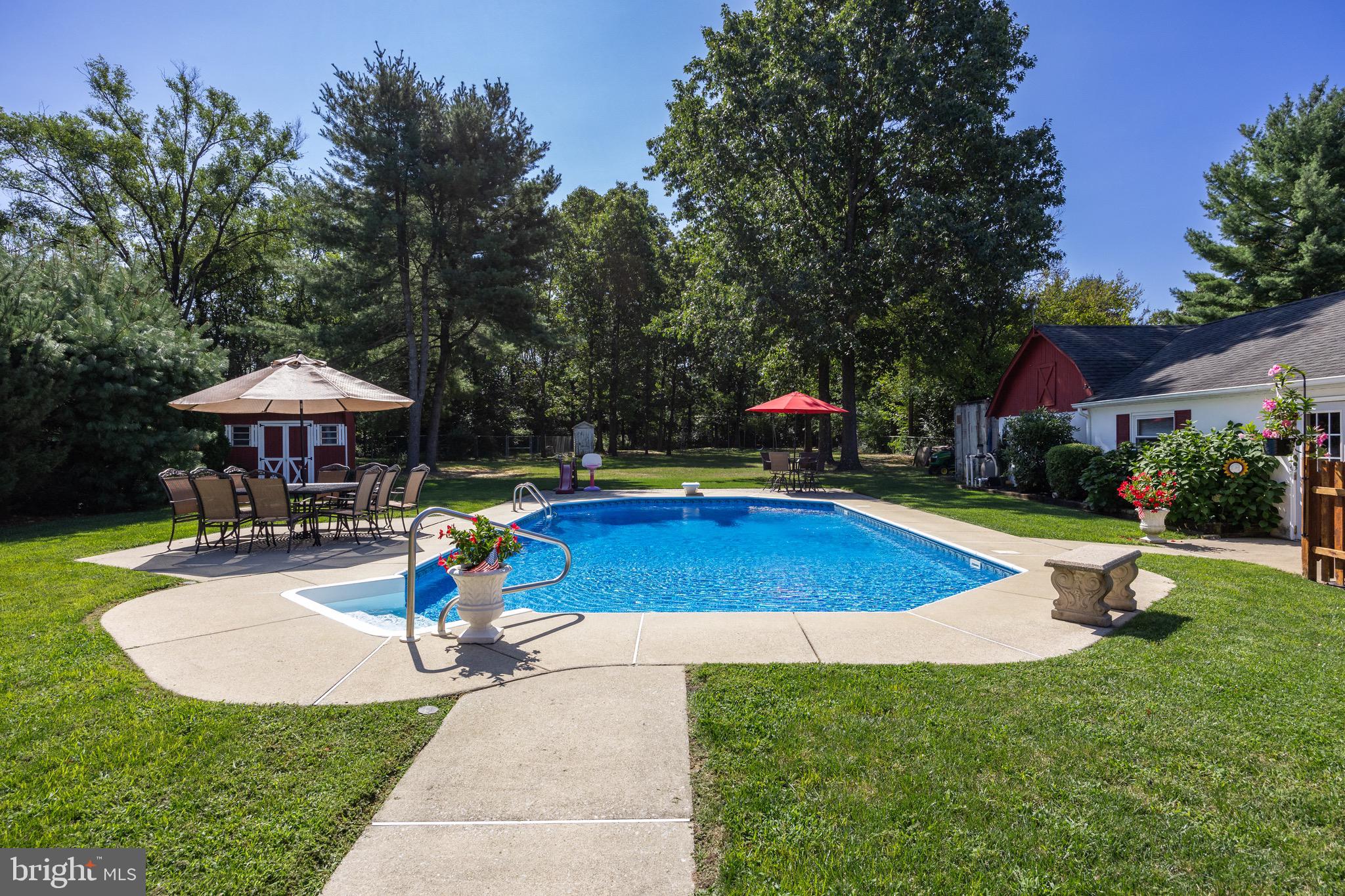 10 Cedar Brook Road Sicklerville, NJ 08081 - Photo 43 of 52 a view of a swimming pool with a table and chairs under an umbrella