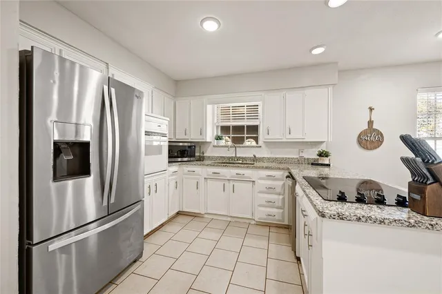 a kitchen with granite countertop a refrigerator stove top oven and sink