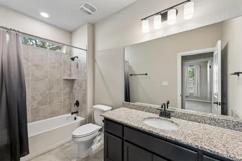 a bathroom with a granite countertop sink toilet mirror and bathtub