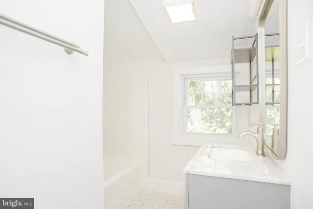 a bathroom with a toilet a sink a vanity a window and mirror