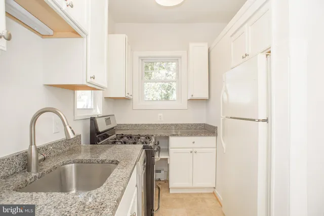 a kitchen with granite countertop a sink stainless steel appliances and a window