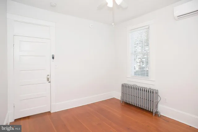 an empty room with wooden floor closet and windows