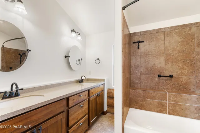 a bathroom with a double vanity sink a mirror and bathtub