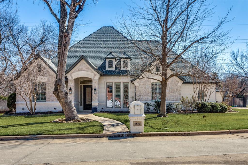 French provincial home with a front lawn, stone siding, and brick siding