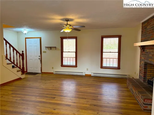 an empty room with wooden floor chandelier and windows