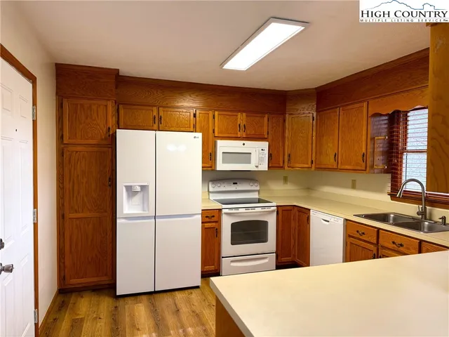 a kitchen with stainless steel appliances granite countertop a refrigerator a sink dishwasher a stove with white cabinets and wooden floor