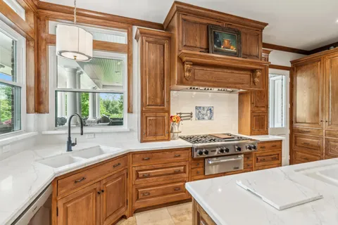 a kitchen with stainless steel appliances granite countertop a stove a sink and a granite counter tops with large windows