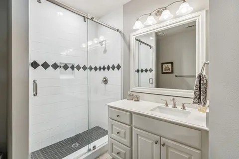 a bathroom with a double vanity sink mirror and shower