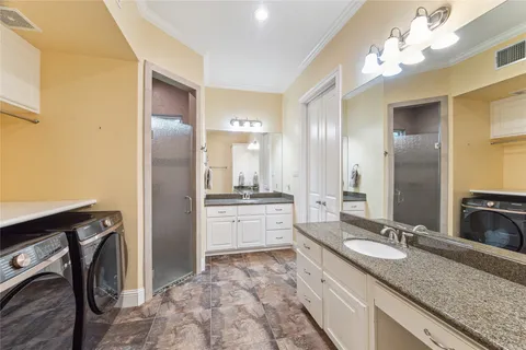 a bathroom with a granite countertop double vanity sink a mirror and a shower