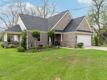 a view of a big house with a big yard potted plants and large tree